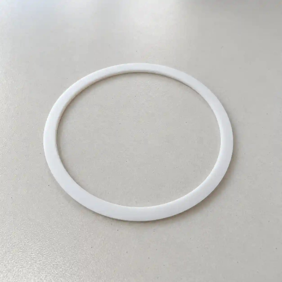 Close-up of a small custom-made plastic PTFE ring with narrow width, designed for precise fitting and durability.